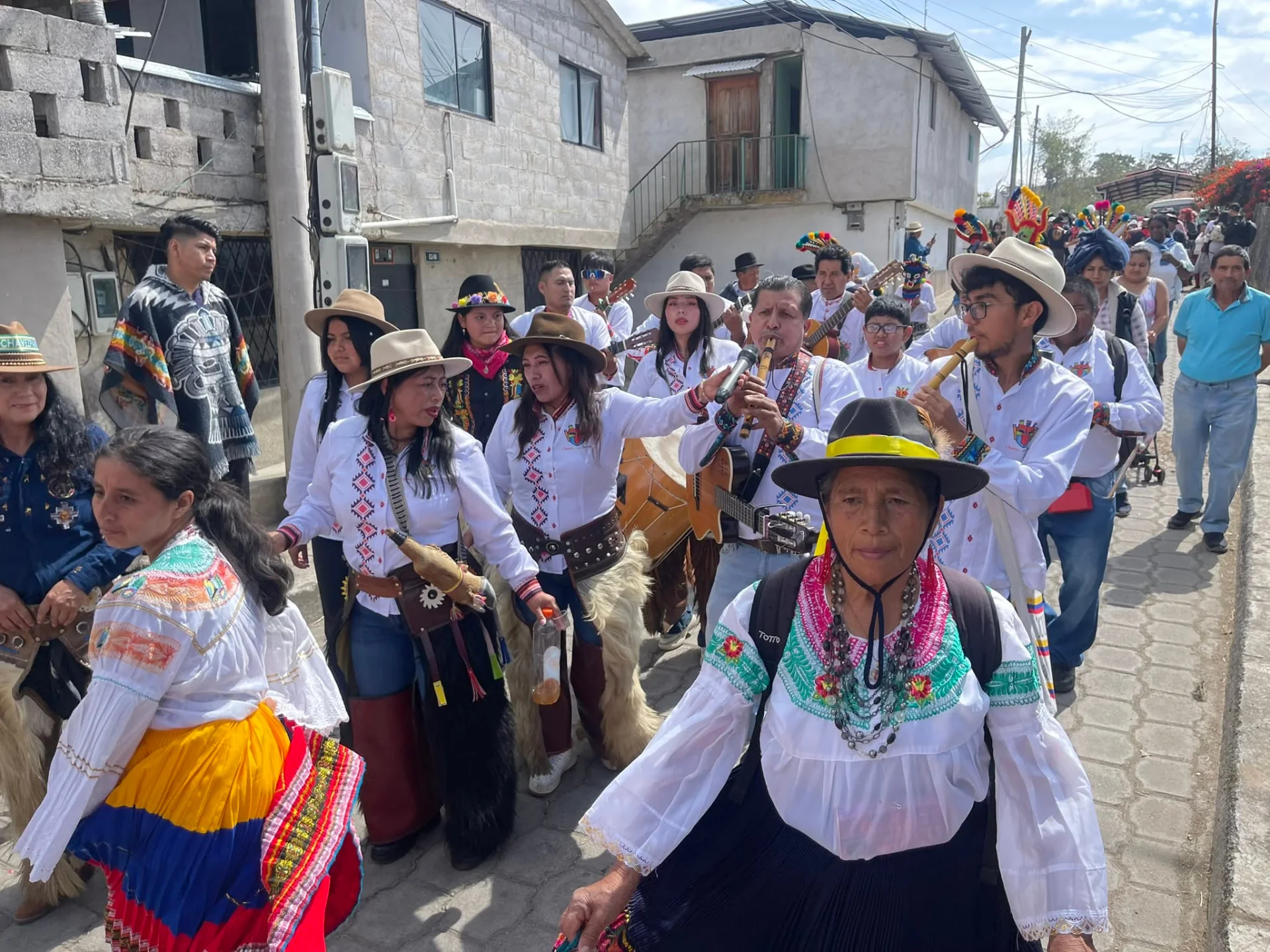 Músicos de Chávez o no Chávez y bailarinas recorren las calles de Chavezpamba durante un desfile festivo.