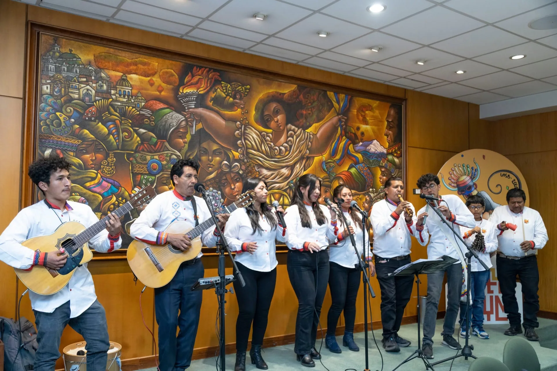 Chávez o no Chávez interpreta música con guitarras, voces y dulzainas frente a un mural.